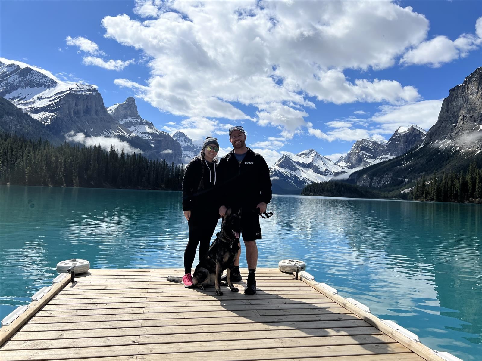 Miss Stone stands with her boyfriend and puppy in front of a crystal blue lake