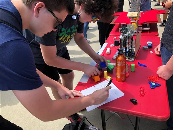 A student signing name on paper to join robotics club